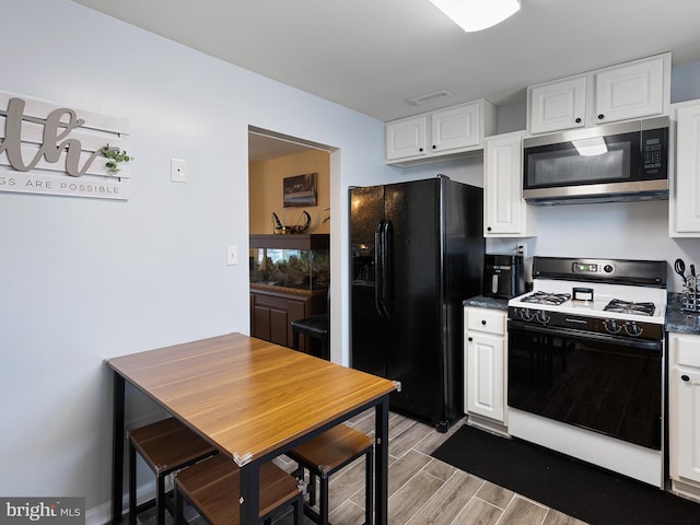 kitchen with white cabinets, light wood-style flooring, stainless steel microwave, black fridge, and white range with gas stovetop