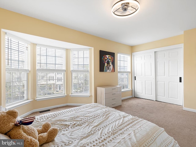 carpeted bedroom with a closet, visible vents, and baseboards