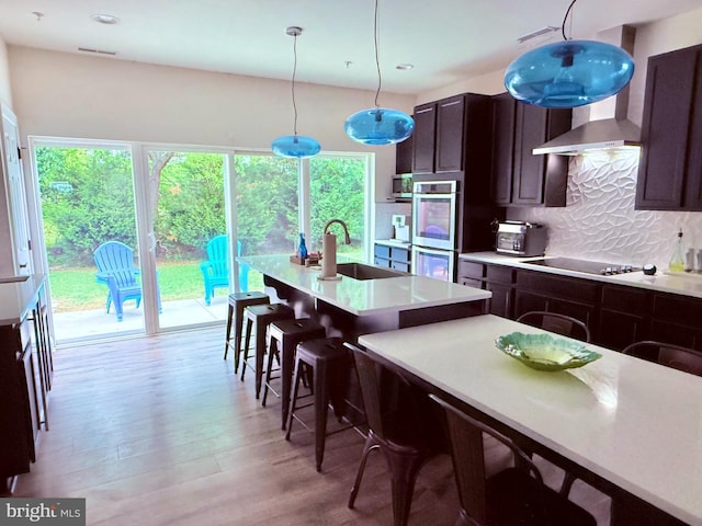 kitchen with stainless steel appliances, a sink, decorative backsplash, light countertops, and light wood-type flooring