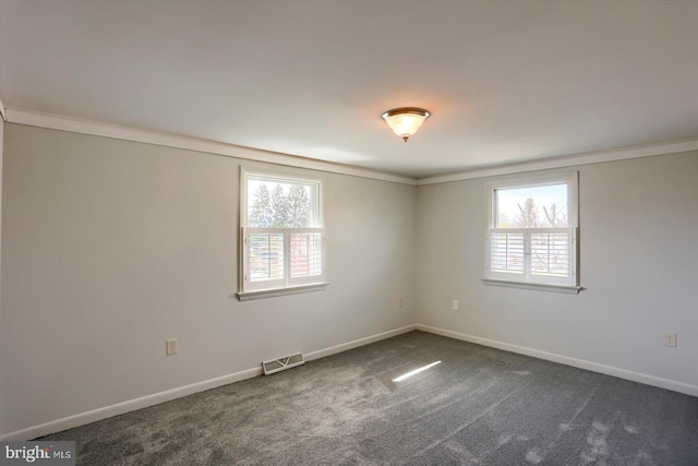empty room featuring baseboards, dark colored carpet, visible vents, and crown molding