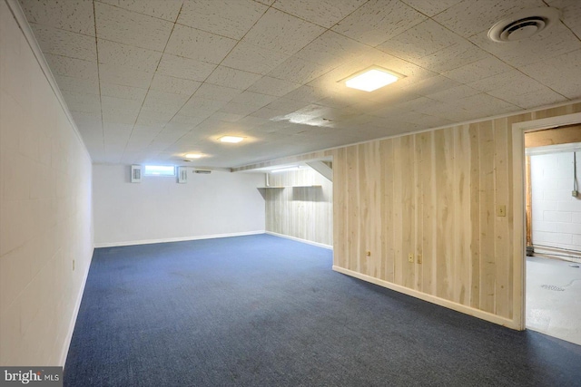 basement with wooden walls, carpet flooring, and visible vents