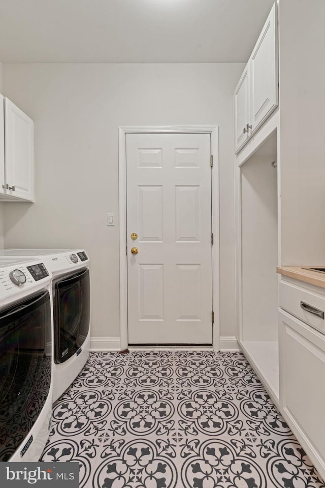laundry area with cabinet space, separate washer and dryer, and baseboards