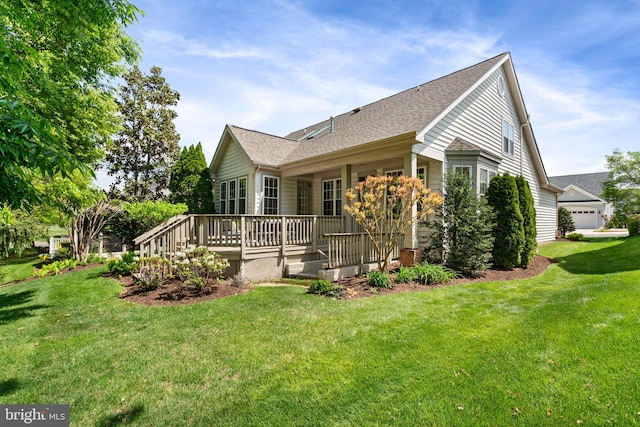 view of side of property featuring roof with shingles, a yard, and a deck