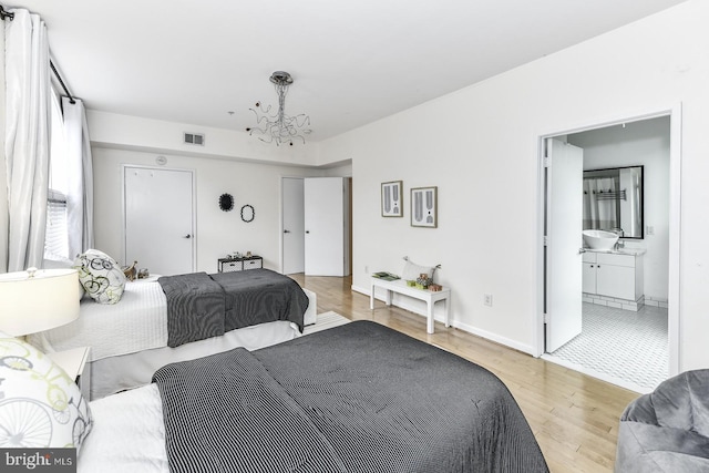 bedroom featuring a chandelier, light wood-style flooring, and baseboards