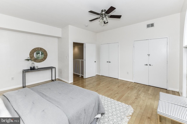 bedroom with multiple closets, hardwood / wood-style floors, baseboards, and ceiling fan