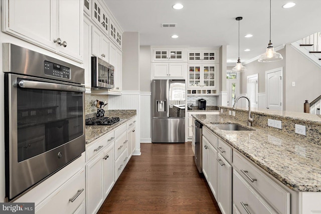 kitchen with backsplash, white cabinetry, stainless steel appliances, and a sink