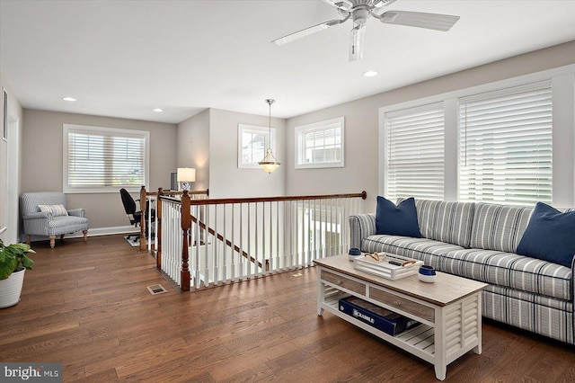 living area featuring dark wood-type flooring, visible vents, ceiling fan, and a healthy amount of sunlight