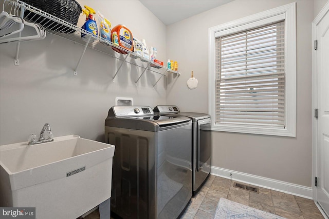 laundry room with washer and clothes dryer, a sink, visible vents, baseboards, and laundry area