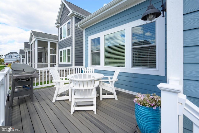 deck featuring grilling area, a sunroom, and outdoor dining space