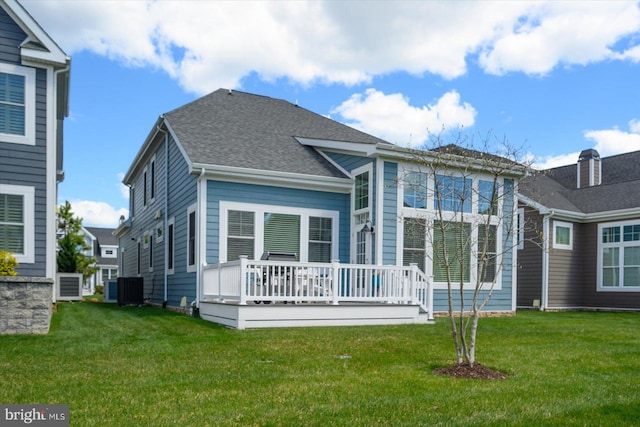 rear view of house with a yard, roof with shingles, central AC, and a deck