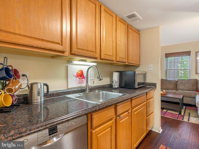 kitchen featuring a sink, dark stone countertops, visible vents, dark wood-style floors, and appliances with stainless steel finishes