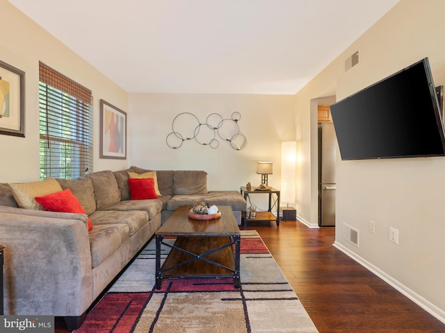 living area featuring baseboards, visible vents, and wood finished floors