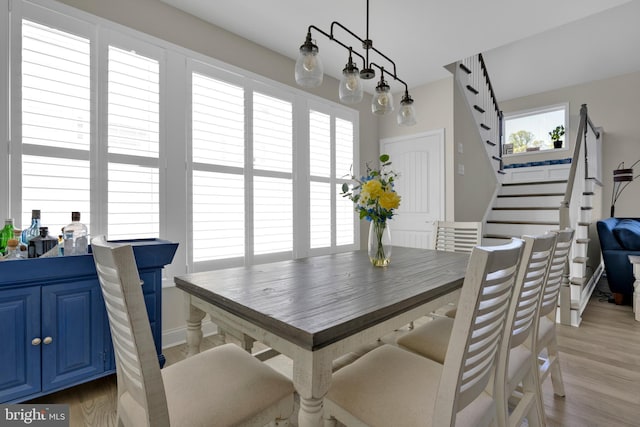 dining area featuring light wood-type flooring and stairs