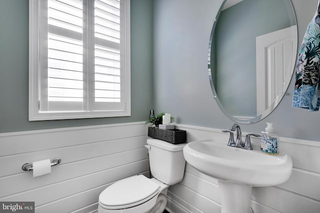 bathroom featuring a sink, wainscoting, and toilet