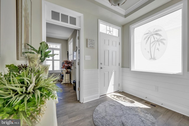 foyer entrance with visible vents, ornamental molding, wood finished floors, and a wealth of natural light