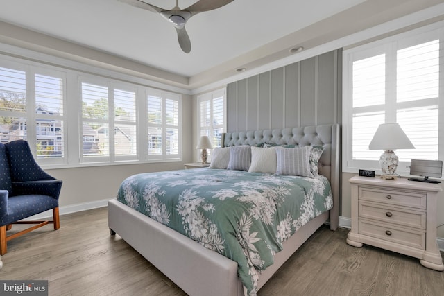 bedroom with baseboards, ceiling fan, multiple windows, and wood finished floors