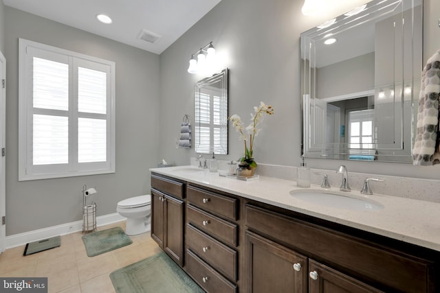 bathroom featuring a sink, baseboards, toilet, and double vanity