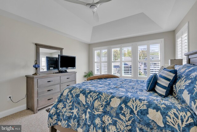 bedroom with a raised ceiling, baseboards, ceiling fan, and light colored carpet