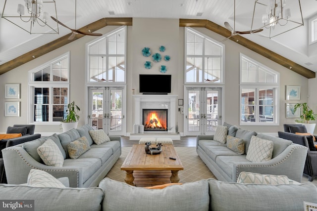 living room featuring a high end fireplace, high vaulted ceiling, french doors, and a notable chandelier