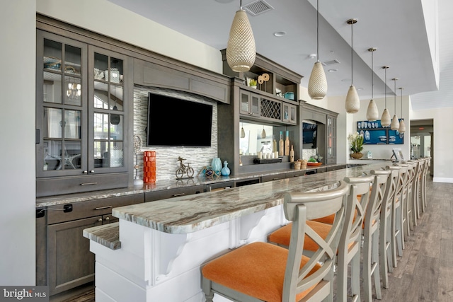 bar featuring visible vents, light wood-style floors, and hanging light fixtures