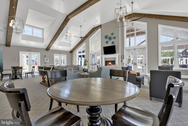 dining space with beam ceiling, carpet floors, high vaulted ceiling, french doors, and a lit fireplace