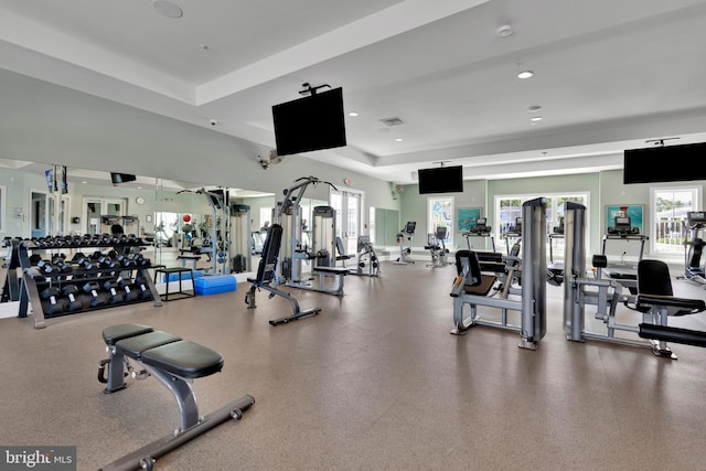 workout area with a tray ceiling, recessed lighting, and visible vents