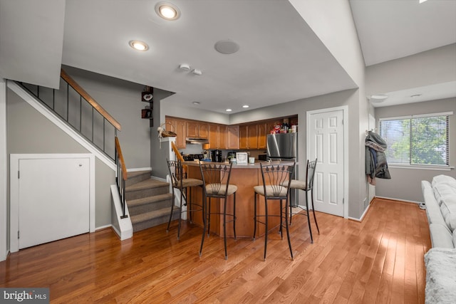 kitchen featuring light wood-style flooring, light countertops, a kitchen bar, baseboards, and recessed lighting