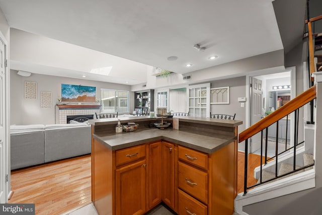 kitchen featuring dark countertops, a tiled fireplace, a skylight, and open floor plan