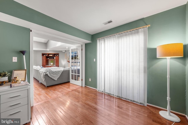 bedroom with light wood-style flooring, visible vents, and baseboards