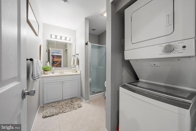 interior space with a sink, stacked washing maching and dryer, light tile patterned floors, baseboards, and laundry area