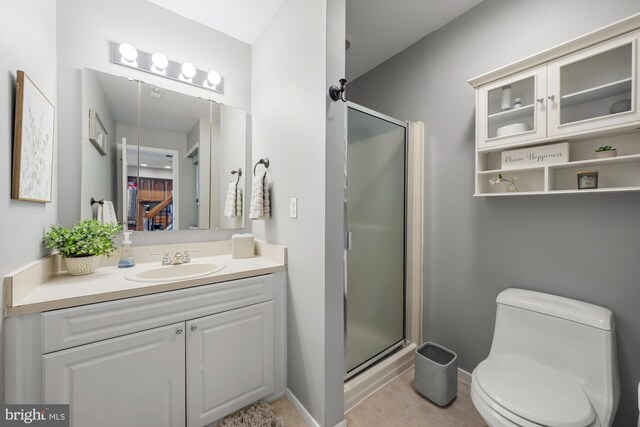 full bath with toilet, a stall shower, vanity, baseboards, and tile patterned flooring
