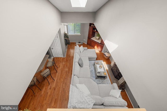 living room with a skylight, baseboards, and light wood-style floors