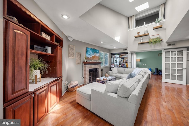 living room with light wood-style flooring, baseboards, visible vents, recessed lighting, and a fireplace