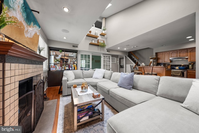 living room featuring recessed lighting, a fireplace with raised hearth, stairs, and visible vents