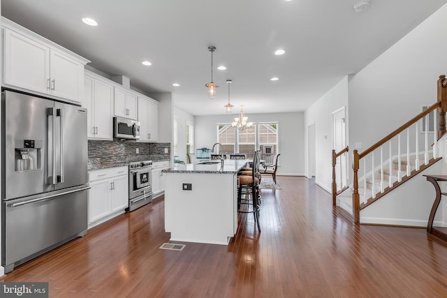 625 E G St, Purcellville, VA 20132 - kitchen with high end appliances, visible vents, light stone countertops, decorative backsplash, and a kitchen island with sink