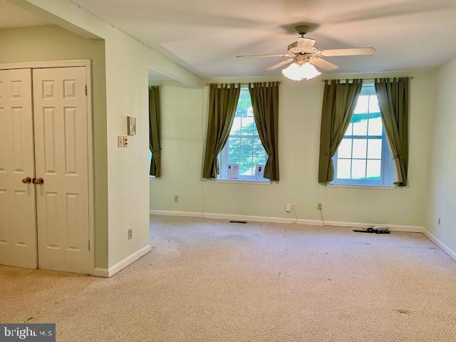 empty room with baseboards, ceiling fan, carpet, and visible vents