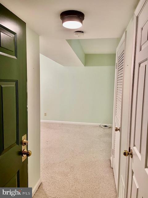 hallway featuring baseboards and light carpet