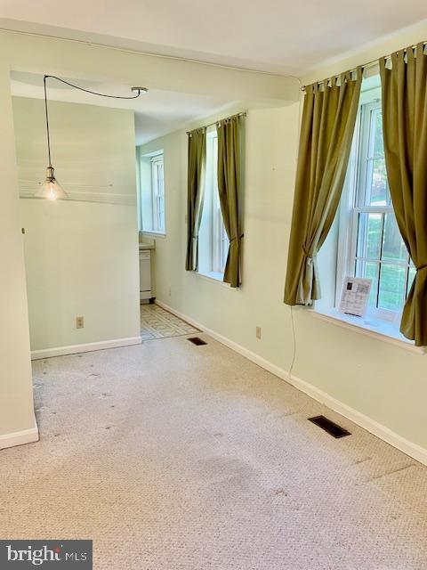 empty room featuring carpet floors, baseboards, and visible vents