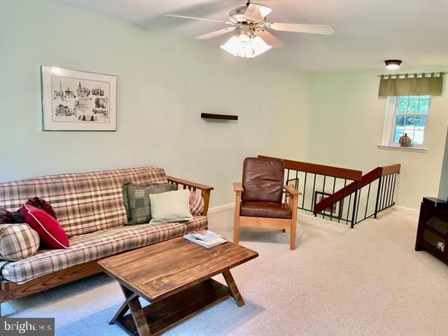living area with baseboards, a ceiling fan, and carpet flooring