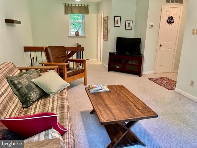 living area with baseboards, visible vents, and carpet