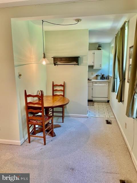 dining room with baseboards, light colored carpet, and visible vents