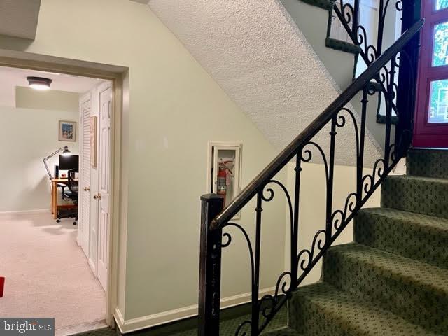 stairway with baseboards, carpet flooring, a textured ceiling, and lofted ceiling
