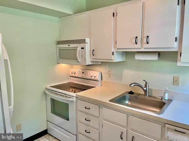 kitchen featuring a sink, white cabinets, white appliances, and light countertops
