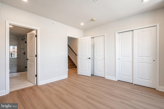 unfurnished bedroom featuring ensuite bath, baseboards, recessed lighting, and two closets