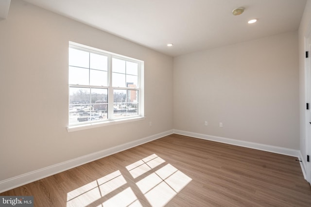empty room with baseboards, wood finished floors, and recessed lighting