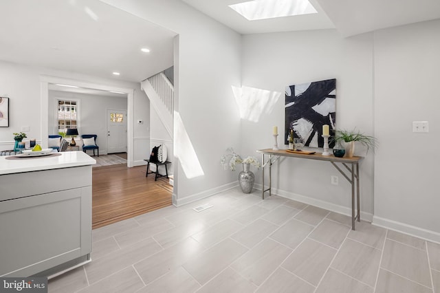 interior space with visible vents, baseboards, recessed lighting, a skylight, and stairs