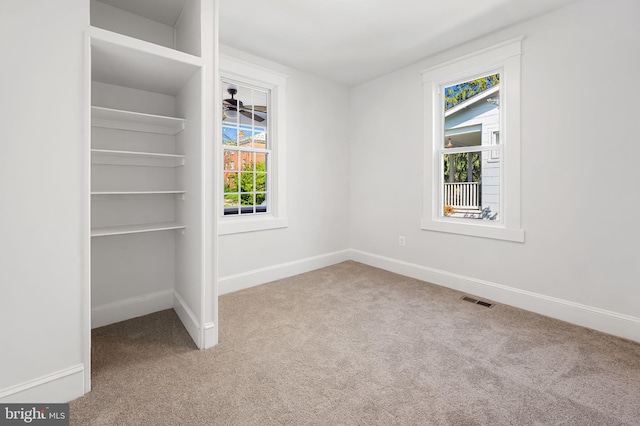 unfurnished bedroom featuring visible vents, multiple windows, and carpet floors