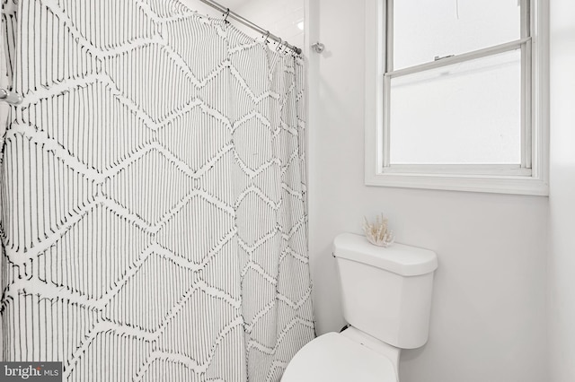 bathroom with toilet and a shower with shower curtain