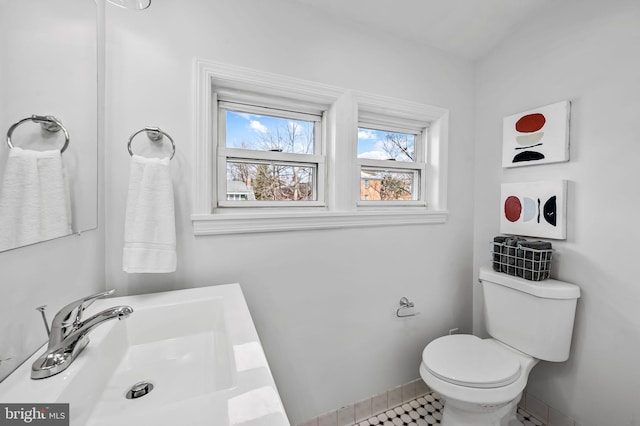 bathroom featuring baseboards, toilet, and a sink