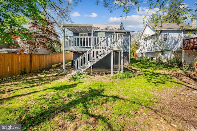 rear view of house featuring a deck, fence, a lawn, and stairs